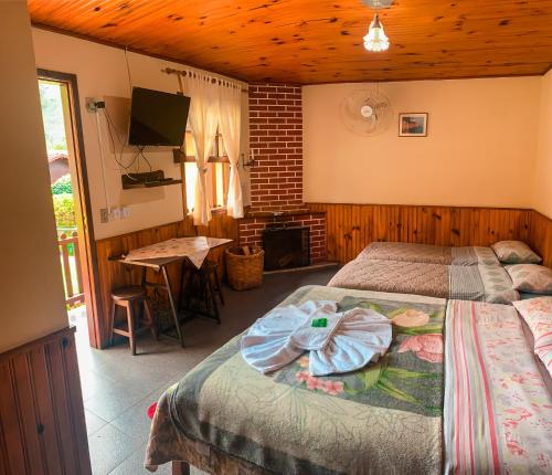 a bedroom with two beds and a table and a television at Pousada Águas Claras in Visconde De Maua