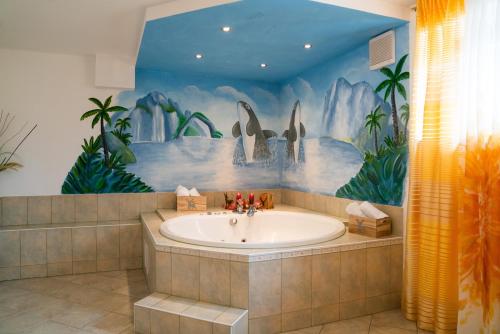 ein Badezimmer mit einer Badewanne und einem Wandbild aus Walen in der Unterkunft Zistelberghof in Werfenweng