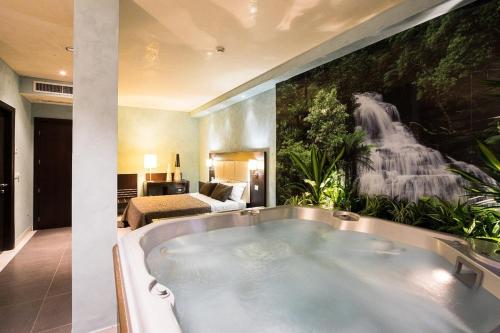 una grande vasca da bagno in una camera con un murale a cascata di La Villa a Pieve a Nievole