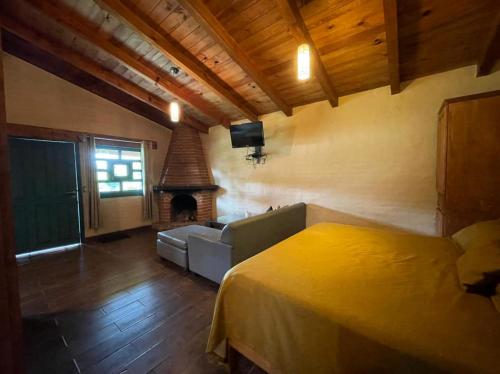 a bedroom with a bed and a couch and a fireplace at cabañas Mazzatl jacuzzy in Mazamitla