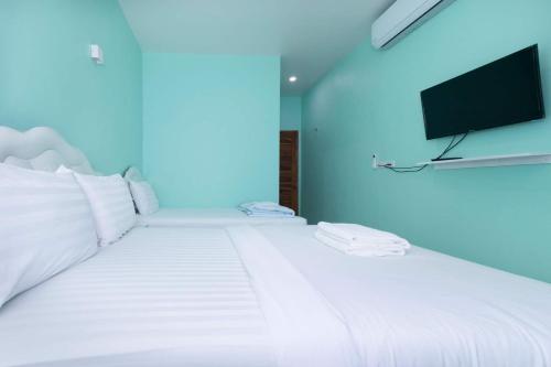 a bedroom with a white bed with a tv on the wall at Lomluang hostel&hotel in Nan