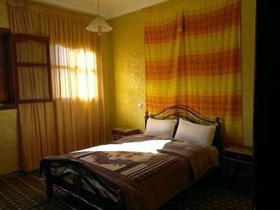 a bedroom with a bed and a colorful wall at Auberge et hôtel les amis tafraout in Tafraoute