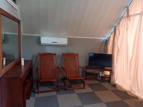 two chairs in a room with a desk and a television at St.Clair Villas in Dimbula