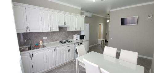 a kitchen with white cabinets and a white table at Apartaments Vityzevo in Vityazevo