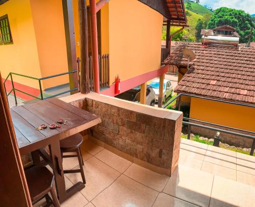 a balcony with a wooden table and a view of a house at Pousada Águas Claras in Visconde De Maua
