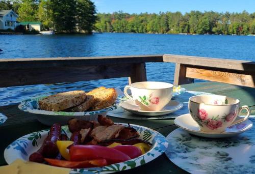 uma mesa com pratos de comida e chávenas de café em Year-round Waterfront Green Cottage On Vert Lake em Val-des-Bois