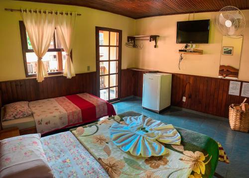 a bedroom with two beds and a tv and a table at Pousada Águas Claras in Visconde De Maua