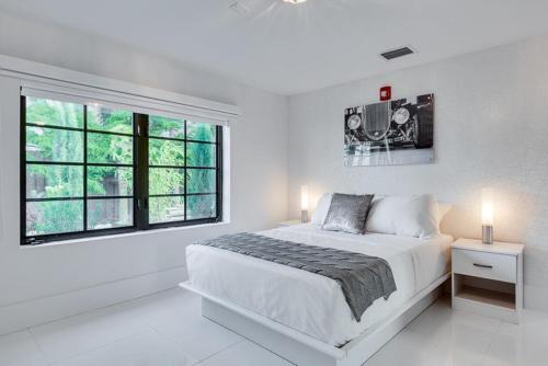 um quarto branco com uma cama grande e 2 janelas em Bars B&B South Beach Hotel em Miami Beach