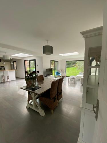 a dining room and living room with a table and chairs at Belle villa contemporaine & lumineuse plage normandie in Luc-sur-Mer