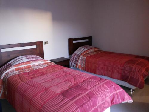 a bedroom with two beds with red comforters at Hostal Atacama North in San Pedro de Atacama