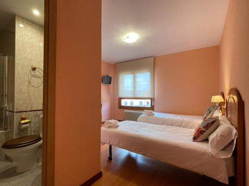 een slaapkamer met 2 bedden, een douche en een toilet bij Hostal Restaurante Torreblanca in Duruelo de la Sierra