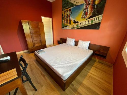 a bedroom with a bed in a red wall at Residencial Avenida Geovanni in São Tomé