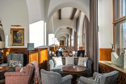 a lobby with chairs and tables in a building at Suvretta House in St. Moritz