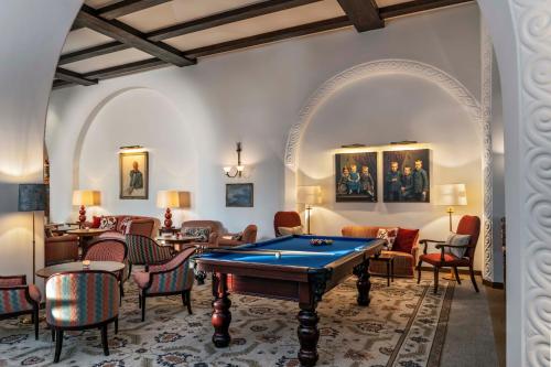 a room with a pool table and chairs at Suvretta House in St. Moritz