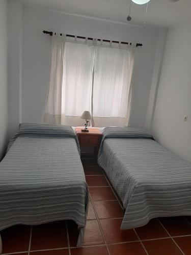 two beds in a room with a window at Pension casa Fina Ruiz in Almuñécar