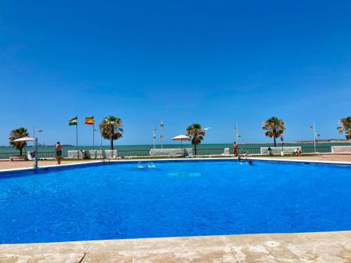 een groot blauw zwembad naast het strand bij ESTUDIO BLEGAMAR VISTAS - Playa, WiFi y Aparcamiento in El Puerto de Santa María