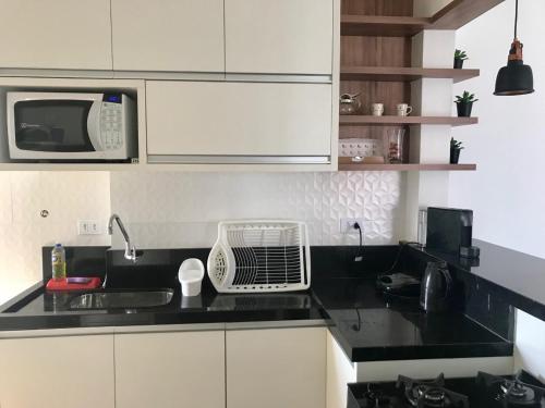 een keuken met een magnetron en een zwart aanrecht bij Apartamento na Enseada com vista para o mar - 300 m da praia in Guarujá