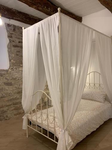 a canopy bed with white curtains in a room at Da Agostino, la casa del latte in Costa di Mezzate