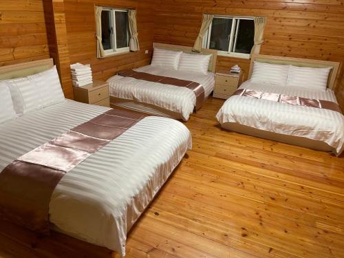 3 Betten in einem Zimmer mit Holzböden in der Unterkunft 桃山渡假農場 in Fuxing