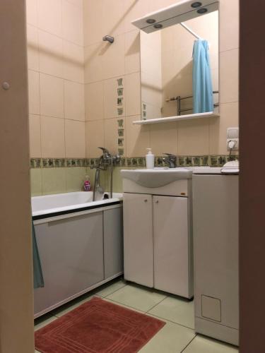 uma casa de banho branca com um lavatório e um espelho em Квартира-студия на Котляра em Kharkov