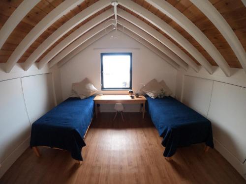 dwa łóżka w pokoju ze stołem i oknem w obiekcie Canto do Nemo w mieście Canto da Areia