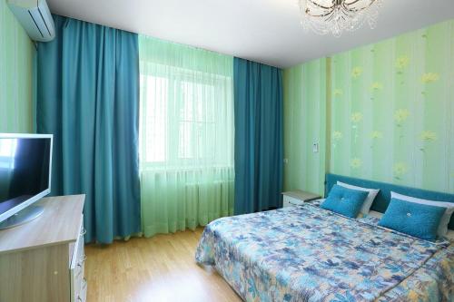 a bedroom with a bed with blue curtains and a television at flat-all 151 Kropotkina двухкомнатная квартира с 7 местами рядом с ТРЦ " Галерея Чижова" in Voronezh