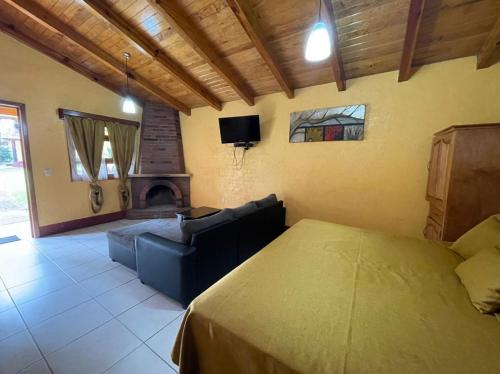 - une chambre avec un lit, un canapé et une cheminée dans l'établissement Cabañas Rosy, à Mazamitla