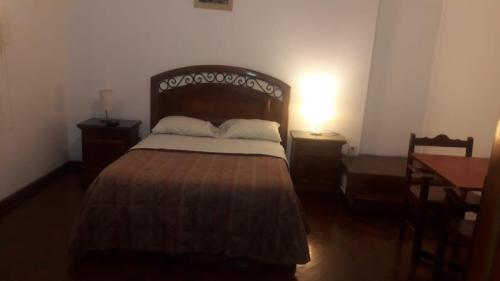 a bedroom with a bed with a wooden headboard and a table at Hospedaje Schell in Lima