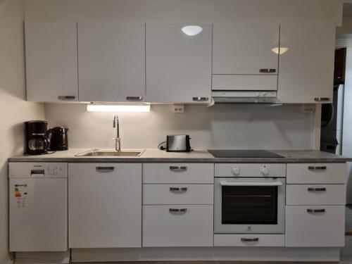 una cocina con armarios blancos y fregadero en Polaris Homes for You, en Rovaniemi