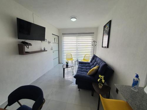 a living room with a blue couch and a tv at Departamento de lujo en Manzanillo, planta baja frente a la alberca in Manzanillo