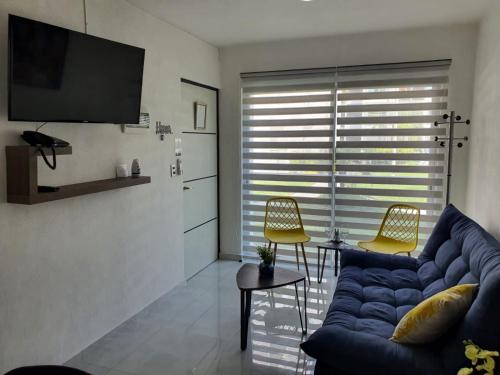 a living room with a blue couch and a tv at Departamento de lujo en Manzanillo, planta baja frente a la alberca in Manzanillo