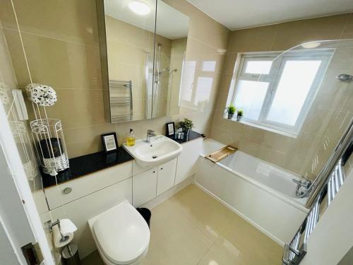 a bathroom with a sink and a toilet and a mirror at Enfield Chase Apartment in Enfield