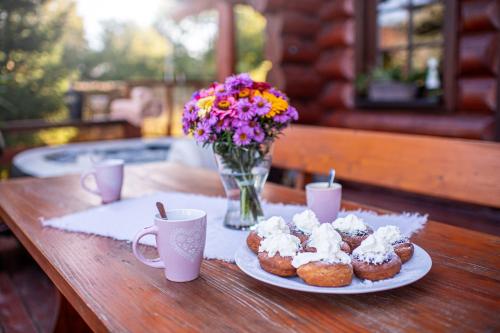 a table with two plates of pastries and a vase of flowers at Srub Blažim in Blažim