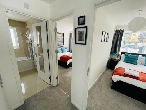 a bedroom with two beds and a bathroom with a mirror at Enfield Chase Apartment in Enfield