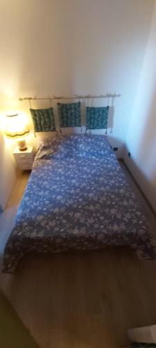 ein Schlafzimmer mit einem Bett mit einer blauen Decke und Kissen in der Unterkunft Idéal pour les vacances in Selonnet