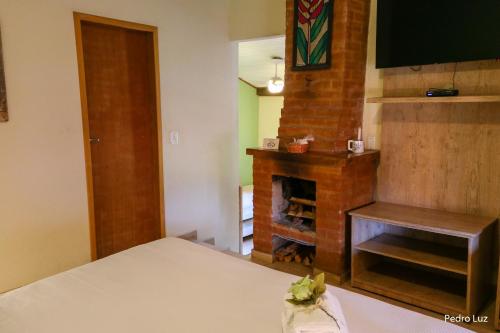 a room with a fireplace and a bed with a table at Pousada Villa Luna in Penedo