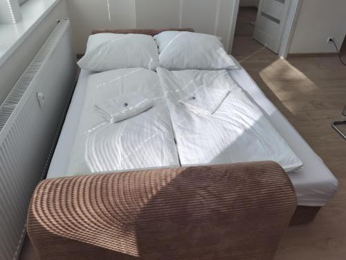 ein weißes Bett mit weißer Bettwäsche und Kissen darauf in der Unterkunft Apartmán RUŽA in Ružomberok