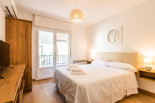 1 dormitorio con 1 cama, TV y ventana en tuGuest San Agustin Apartment, en Granada