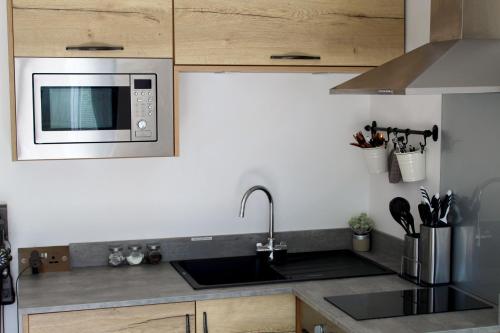 a kitchen with a sink and a microwave at One One Five Apartment in Swansea