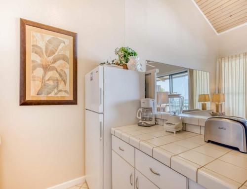 a kitchen with a white refrigerator and a mirror at Mahina Surf - Lahaina, HI by TS in Lahaina