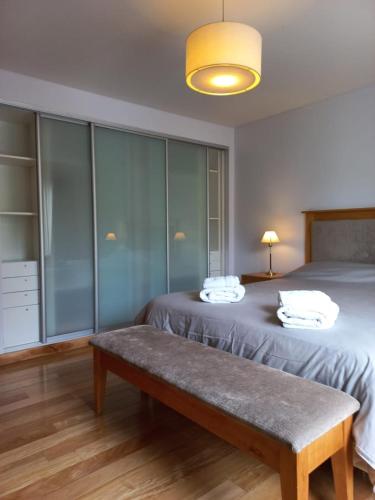 Schlafzimmer mit einem Bett mit einer Bank in der Unterkunft Departamento Centro San Martin de los Andes in San Martín de los Andes