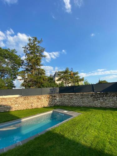 - une piscine dans une cour à côté d'un mur en pierre dans l'établissement La Maison du Grand Four, à Mercurey