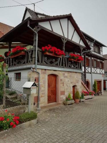 a building with red flowers on the top of it at Gîte HAURY in Cleebourg