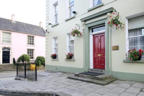 een rode deur aan de zijkant van een wit huis bij Charlemont House Exclusive Hire Perfect for Groups of 8 to 23 persons in Moy