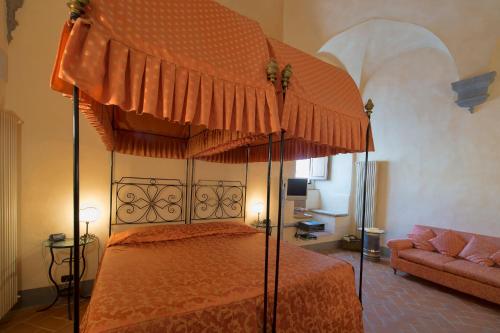 um quarto com uma cama de dossel e um sofá em Contucci Residenze d'Epoca em Montepulciano