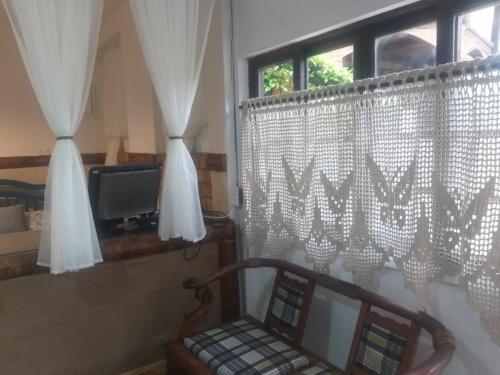 a room with a window with curtains and a chair at Chalé do lago Ladeira de Pedra in Salesópolis