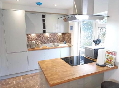 a kitchen with white cabinets and a wooden counter top at Spectacular 4 Bedroom Sea View Residential Home in Bangor