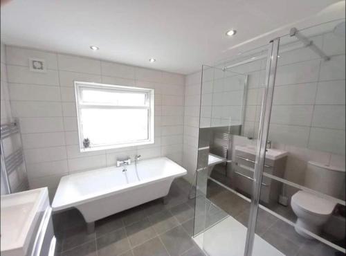 ein Badezimmer mit einer Badewanne, einem Waschbecken und einem WC in der Unterkunft Spectacular 4 Bedroom Sea View Residential Home in Bangor