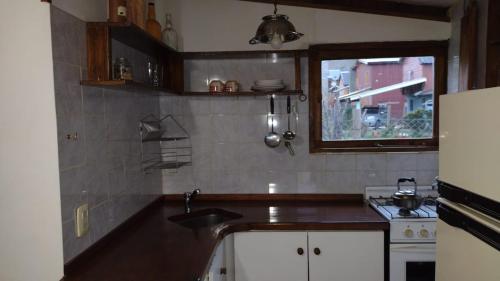 una pequeña cocina con fregadero y ventana en La Casita en San Martín de los Andes