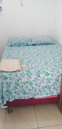 a bed with a blue and white comforter on it at Pousada águas belas in Carolina